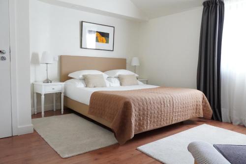 Schlafzimmer mit einem Bett mit weißer Bettwäsche und Kissen in der Unterkunft Quinta de Anterronde in Arouca