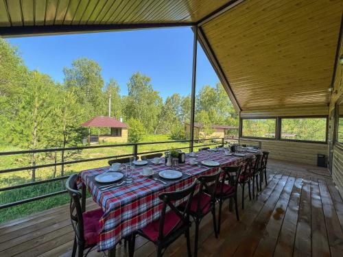 a long table with chairs on a wooden deck at Земляничная поляна Боровое in Shchuchinskiy