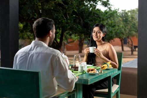 a man and a woman sitting at a table eating food at Jetwing Jungle Lodge, A Luxury Reserve in Yala