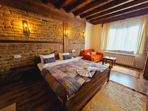 a bedroom with a large bed and a brick wall at Панорама хаус Лещен и еко къщи Дървена и Землянка in Leshten