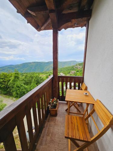 a wooden bench on a balcony with a view at Панорама хаус Лещен и еко къщи Дървена и Землянка in Leshten