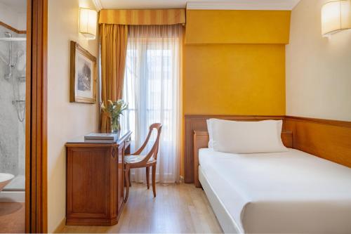 a bedroom with a bed and a desk and a bathroom at UNAHOTELS Galles Milano in Milan