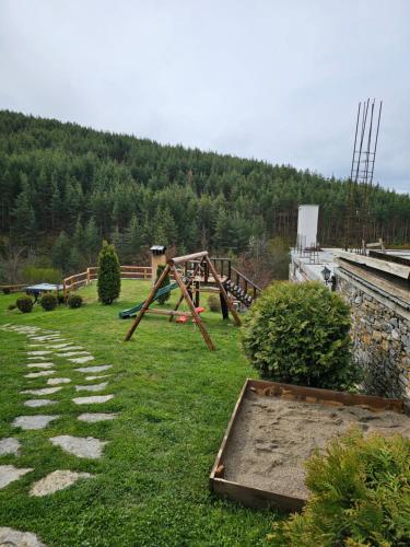 a park with a swing set in the grass at Панорама хаус Лещен и еко къщи Дървена и Землянка in Leshten