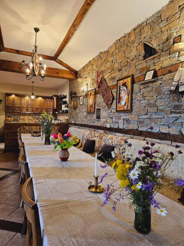a long table in a room with a stone wall at Панорама хаус Лещен и еко къщи Дървена и Землянка in Leshten