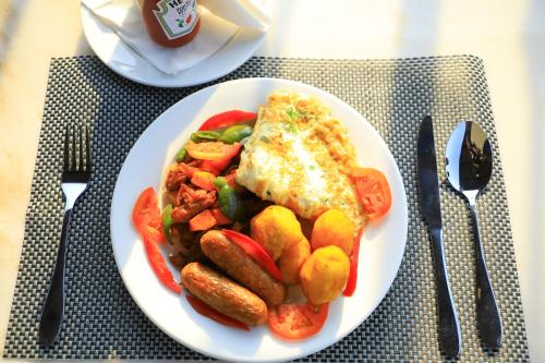 a plate of breakfast food with eggs sausage and vegetables at Galaxy Motel Kampala in Kampala