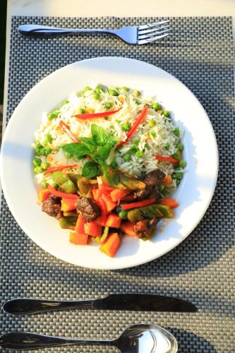 a white plate of food with vegetables on a table at Galaxy Motel Kampala in Kampala