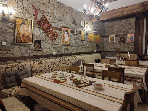 a restaurant with tables and chairs and a stone wall at Панорама хаус Лещен и еко къщи Дървена и Землянка in Leshten