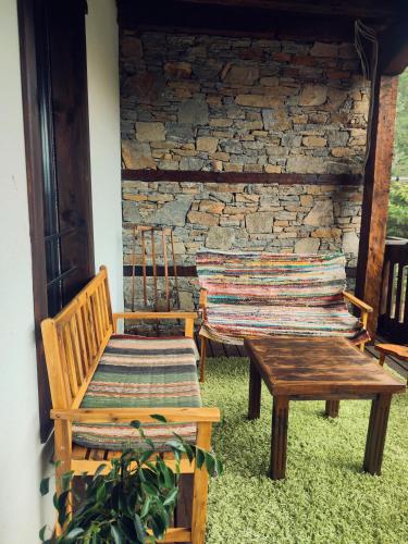 two benches and a table in front of a stone wall at Панорама хаус Лещен и еко къщи Дървена и Землянка in Leshten