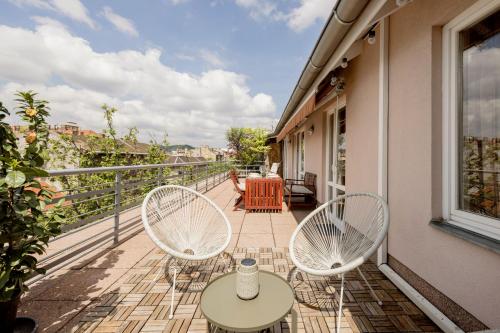 uma varanda com duas cadeiras e uma mesa num edifício em Bright and Spacious Penthouse w/ Terrace & Parking em Budapeste