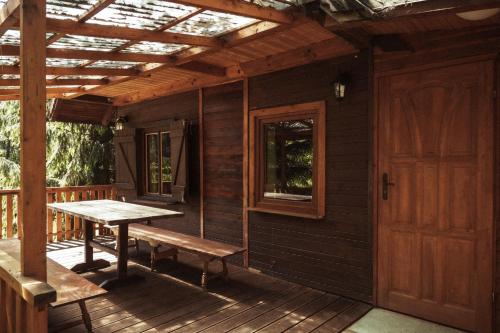- une terrasse couverte en bois avec une table et un banc dans l'établissement Ośrodek Wypoczynkowy Hartek, à Ostaszewo