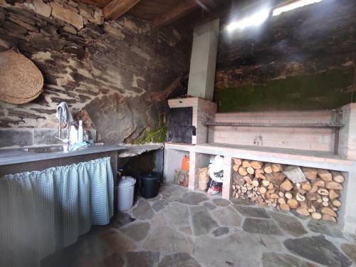 eine Küche mit einer Theke und einem Herd mit Holzscheiten in der Unterkunft PiluPeta Casa de Aldea 
