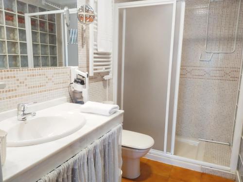een badkamer met een wastafel, een toilet en een douche bij PARAISO ESTAÑO, Terraza PRIMERA LINEA DE PLAYA in Gijón