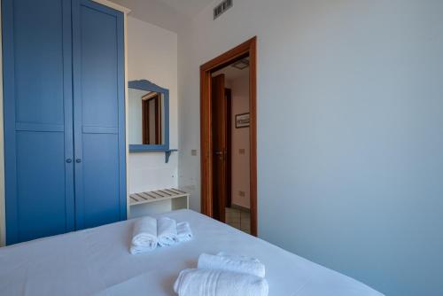 a bedroom with a white bed with towels on it at Residence L'Arcipelago Appartamenti Fronte Mare con Ampio Balcone in Capo dʼOrlando