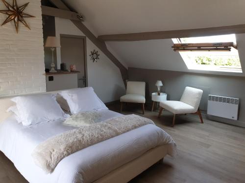 une chambre avec un grand lit blanc et deux chaises dans l'établissement Studio des Enfants, à Honfleur