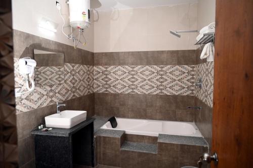 a bathroom with a bath tub and a sink at Hotel Singla Residency in Kangra