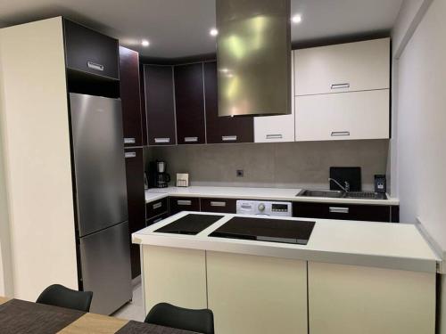 a kitchen with white cabinets and a black refrigerator at Varkiza Lux Apartment in Varkiza