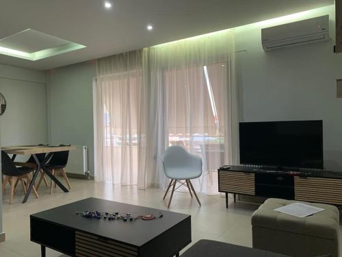 a living room with a couch and a table and a television at Varkiza Lux Apartment in Varkiza