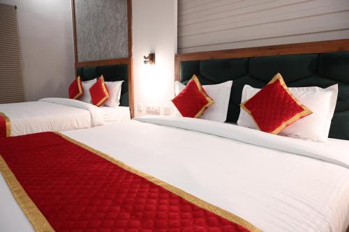 two beds in a hotel room with red pillows at Hotel Singla Residency in Kangra