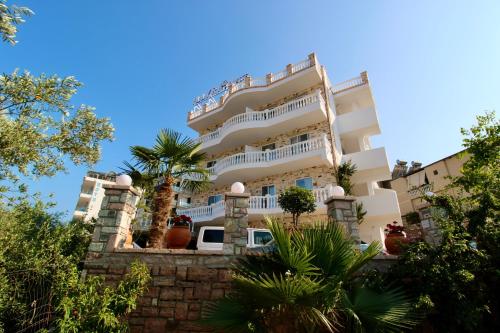 a large white building with a palm tree in front of it at ILLYRIAN hotel Ksamil in Ksamil