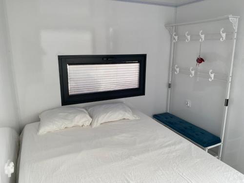 Un pequeño dormitorio con una cama blanca y una ventana en Houseboat Cádiz El Puerto - Casa Flotante, en El Puerto de Santa María