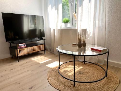 a living room with a tv and a glass table at Bright & central for 4 incl workspace in Bochum