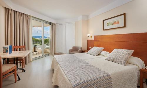 um quarto de hotel com uma cama, uma mesa e uma varanda em Hipotels Bahía Grande Aparthotel em Cala Millor