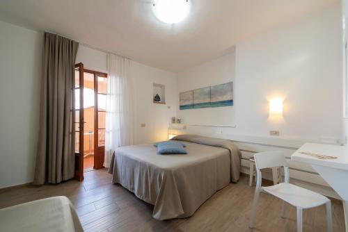a bedroom with a bed and a table and chairs at Albergo Le Briciole in Procchio