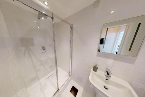 ein weißes Badezimmer mit Dusche und Waschbecken in der Unterkunft ILFRACOMBE SEA ROCK 4 1 Bedroom in Ilfracombe