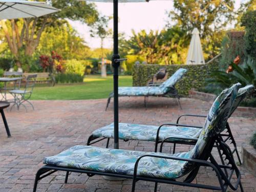 - deux chaises assises sur une terrasse avec un parasol dans l'établissement Malcolm Lodge, à Kingsmead