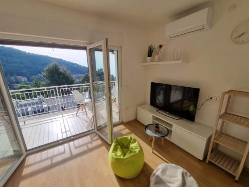 a living room with a television and a balcony at Seaview Apartment Luka with free private parking in Mošćenička Draga in Mošćenička Draga