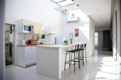 a kitchen with white cabinets and bar stools at شاليهات المرفأ Almarfa Resort in Jeddah