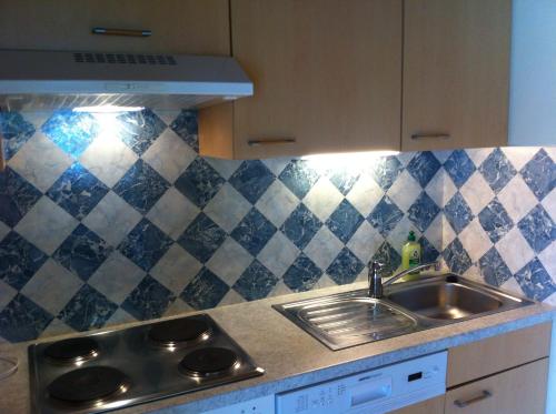 a kitchen with a sink and a tiled wall at Ferienwohnungen Wutte Josefine in Sankt Kanzian