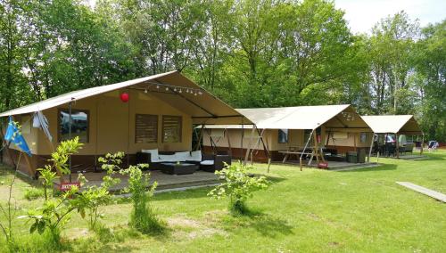 ein großes Gebäude mit einer Veranda im Hof in der Unterkunft Safaritent Kvikkjokk Vledder, locatie Kraanvogels 3 in Vledder