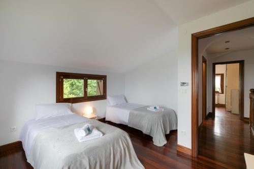 um quarto com 2 camas com lençóis brancos e uma janela em Ezkialderdi - baskeyrentals em Aia