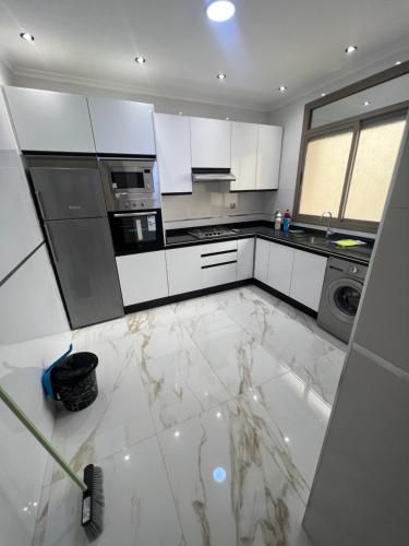a kitchen with white cabinets and a marble floor at Appartements de luxe 4 in Nador