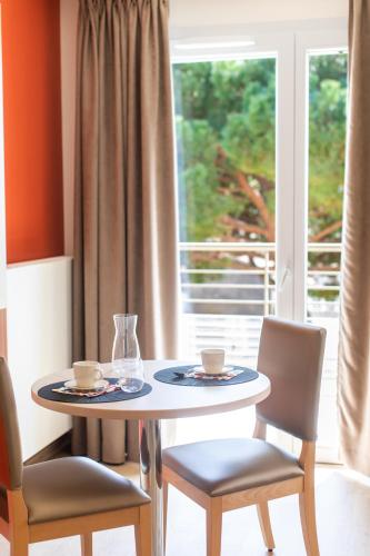 a table with two cups and chairs and a window at ZENAO Fréjus in Fréjus