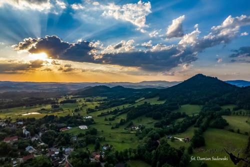 a village in the mountains under a cloudy sky at sunset at Pokoje pod Krzywym Dachem in Karpniki
