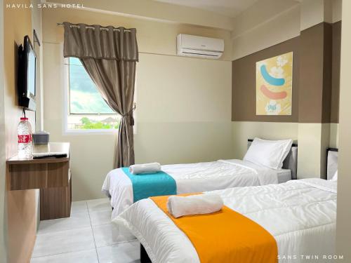 a hotel room with two beds and a window at Sans Hotel Havila Bengkulu in Bengkulu