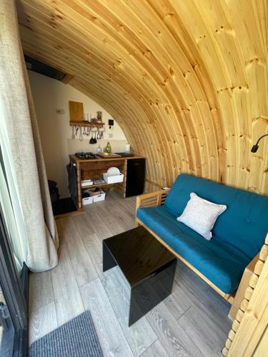 een kamer met een blauwe bank en een tafel bij Henny Riverside Glamping in Sudbury