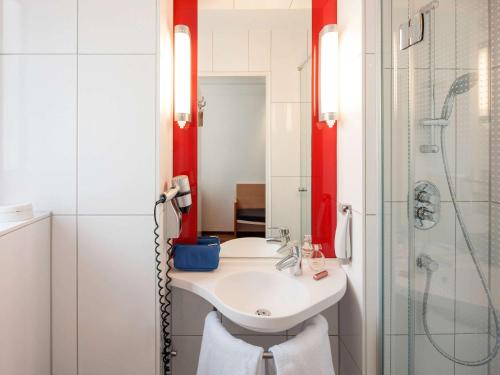 ニュルンベルクにあるイビス ホテル ニュルンベルク シティの白いバスルーム(シンク、シャワー付)
