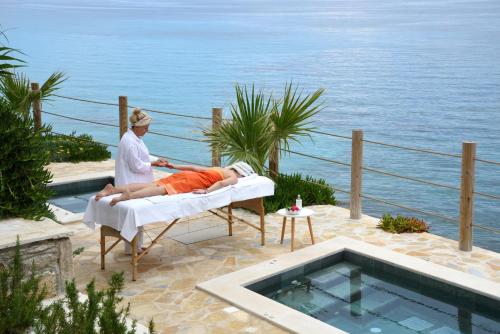 a man laying on a bed next to a pool at Paradisso Beach Villas in Zakynthos Town
