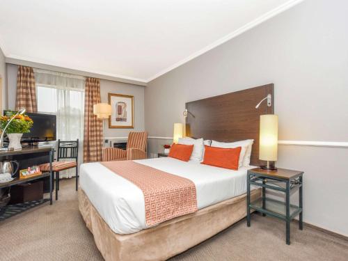 a hotel room with a large bed and a desk at Mercure Johannesburg Midrand in Midrand