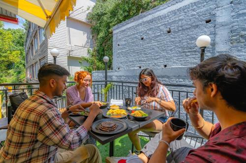 Un gruppo di persone seduti intorno a un tavolo che mangiano cibo di The Hosteller Mussoorie, Mall Road a Mussoorie