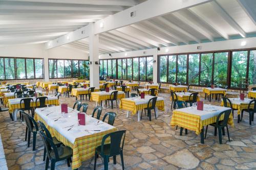 una sala da pranzo con tavoli, sedie e finestre di Azienda Agrituristica Scalelle a Otranto