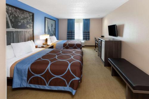 a hotel room with two beds and a flat screen tv at Super 8 by Wyndham Garland Rowlett East Dallas Area in Garland