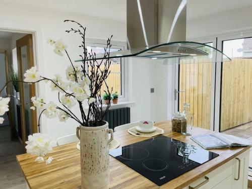 a vase with white flowers on a kitchen counter at Charming Cottage close to M4 Bridgend in Bridgend