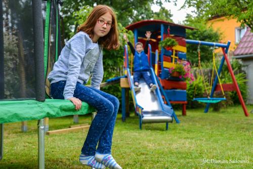 a young girl sitting on a trampoline on a playground at Pokoje pod Krzywym Dachem in Karpniki