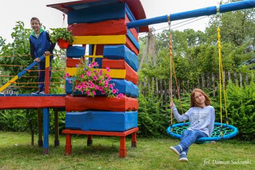 a girl sitting on a swing in a playground at Pokoje pod Krzywym Dachem in Karpniki