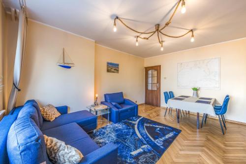 - un salon avec un canapé bleu et une table dans l'établissement Bosman Apartment Gdynia, à Gdynia