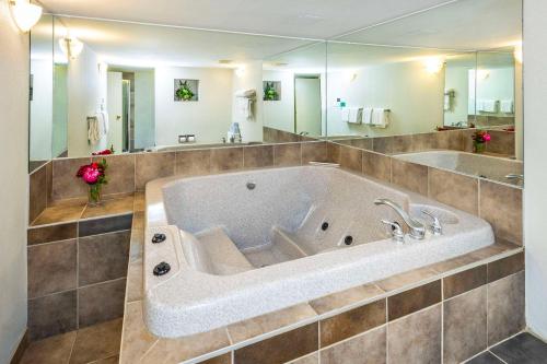 La salle de bains est pourvue d'une grande baignoire et d'un grand miroir. dans l'établissement Comfort Inn & Suites, à Edmonton